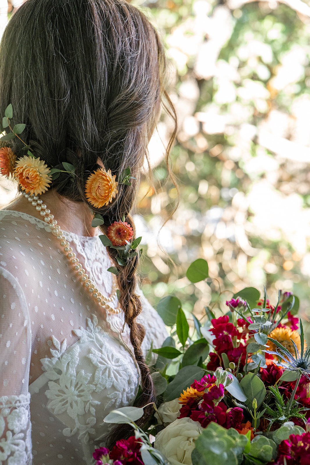 A bride with braided hair with flowers in her hair holding a bouqet