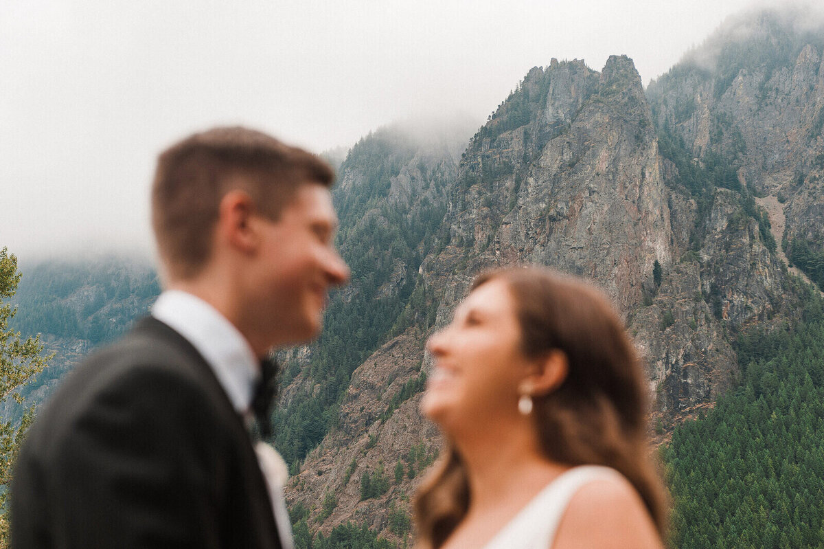 A bride and groom smile at each other as Mt Si towers behind them on their wedding day