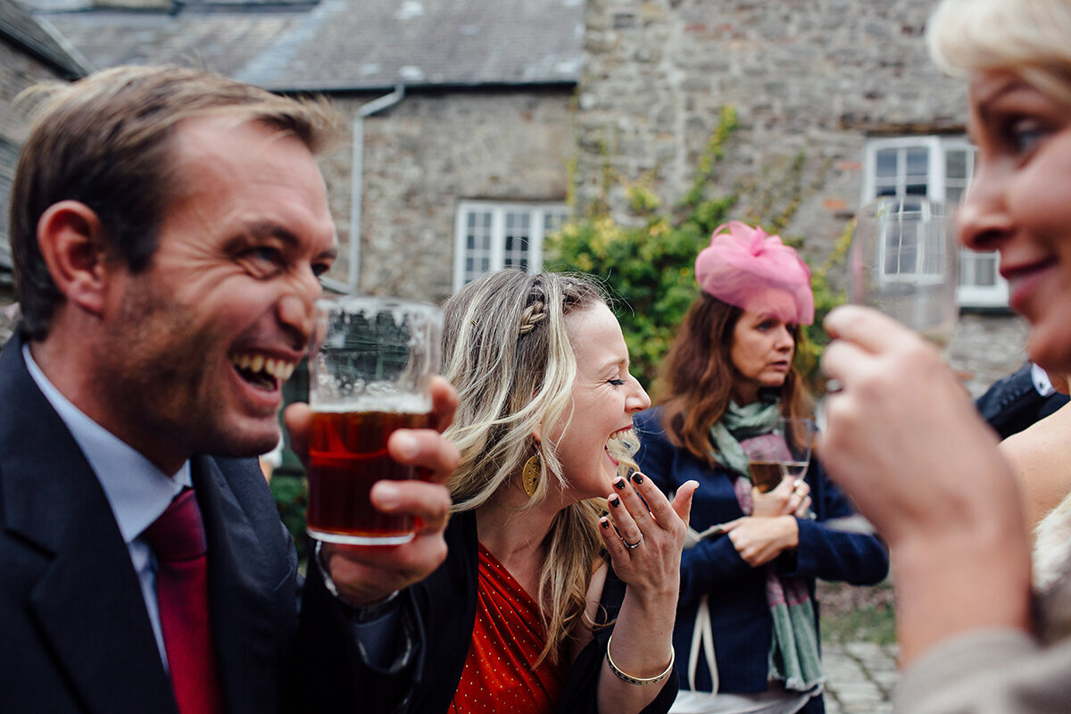 Guests laugh during drinks reception at wedding