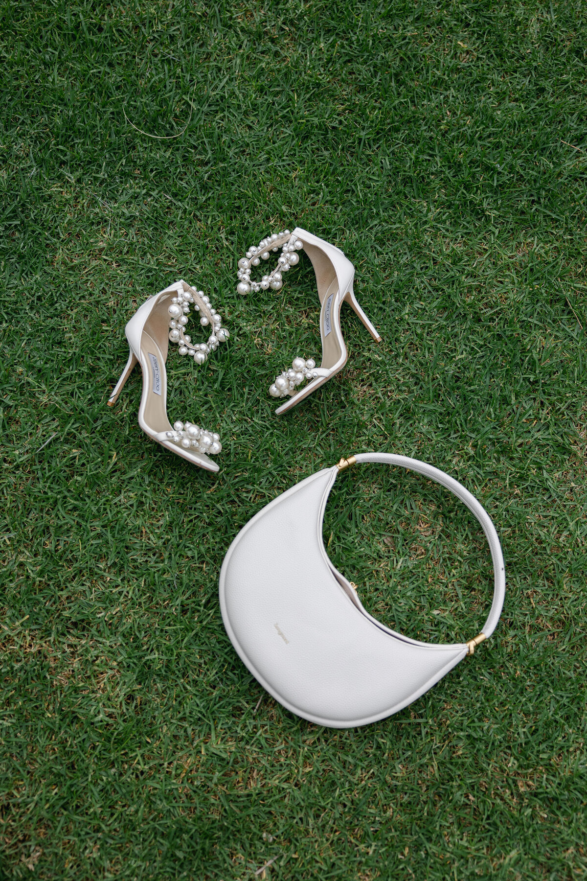 Elegant bridal shoes and a stylish purse elegantly arranged together, showcasing the details of a San Diego wedding in La Jolla.