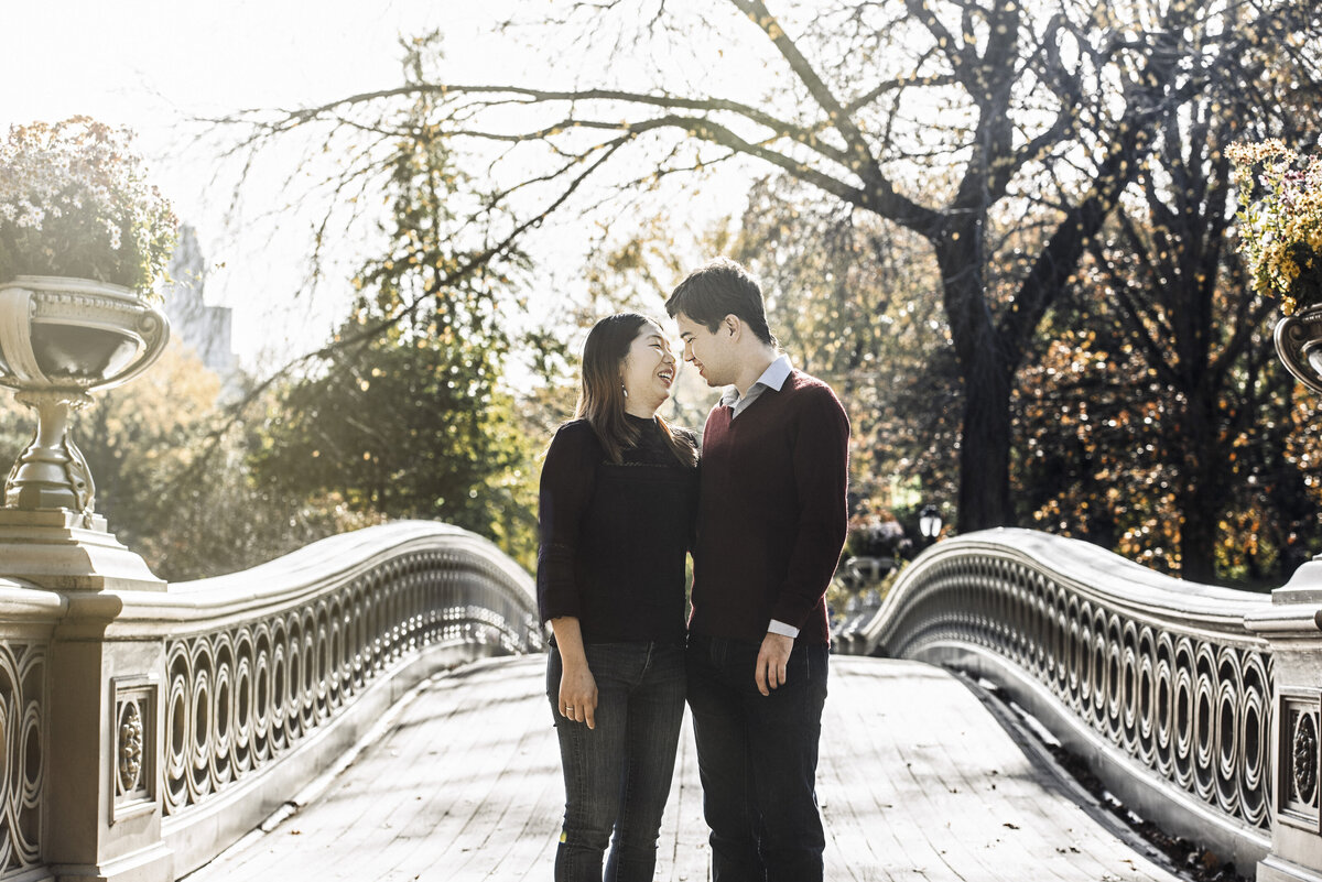 A couple about to kiss while standing at the edge of a bridge