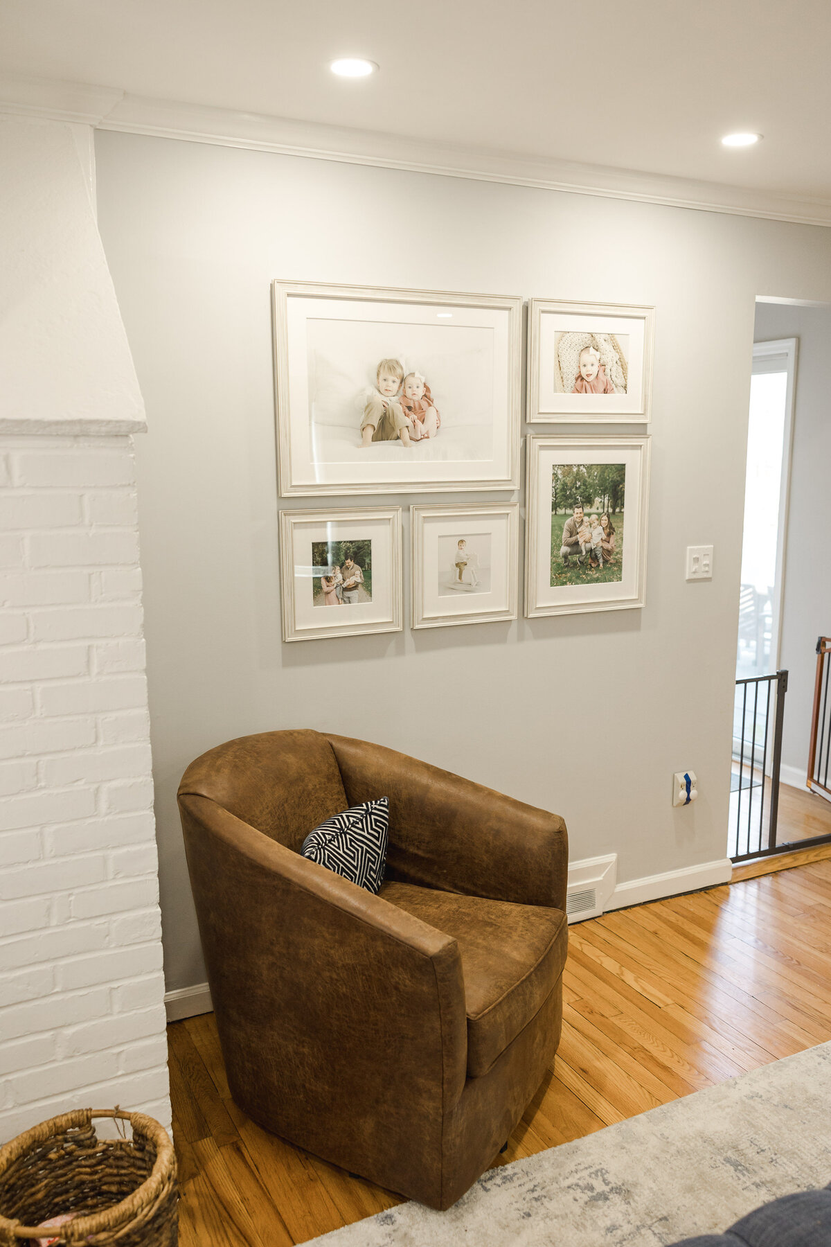 Gallery wall of framed family portraits hanging over a leather chair