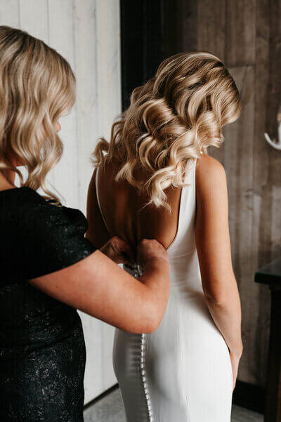 Mother of bride helping zip bride's dress planned by best wedding planners in chicago