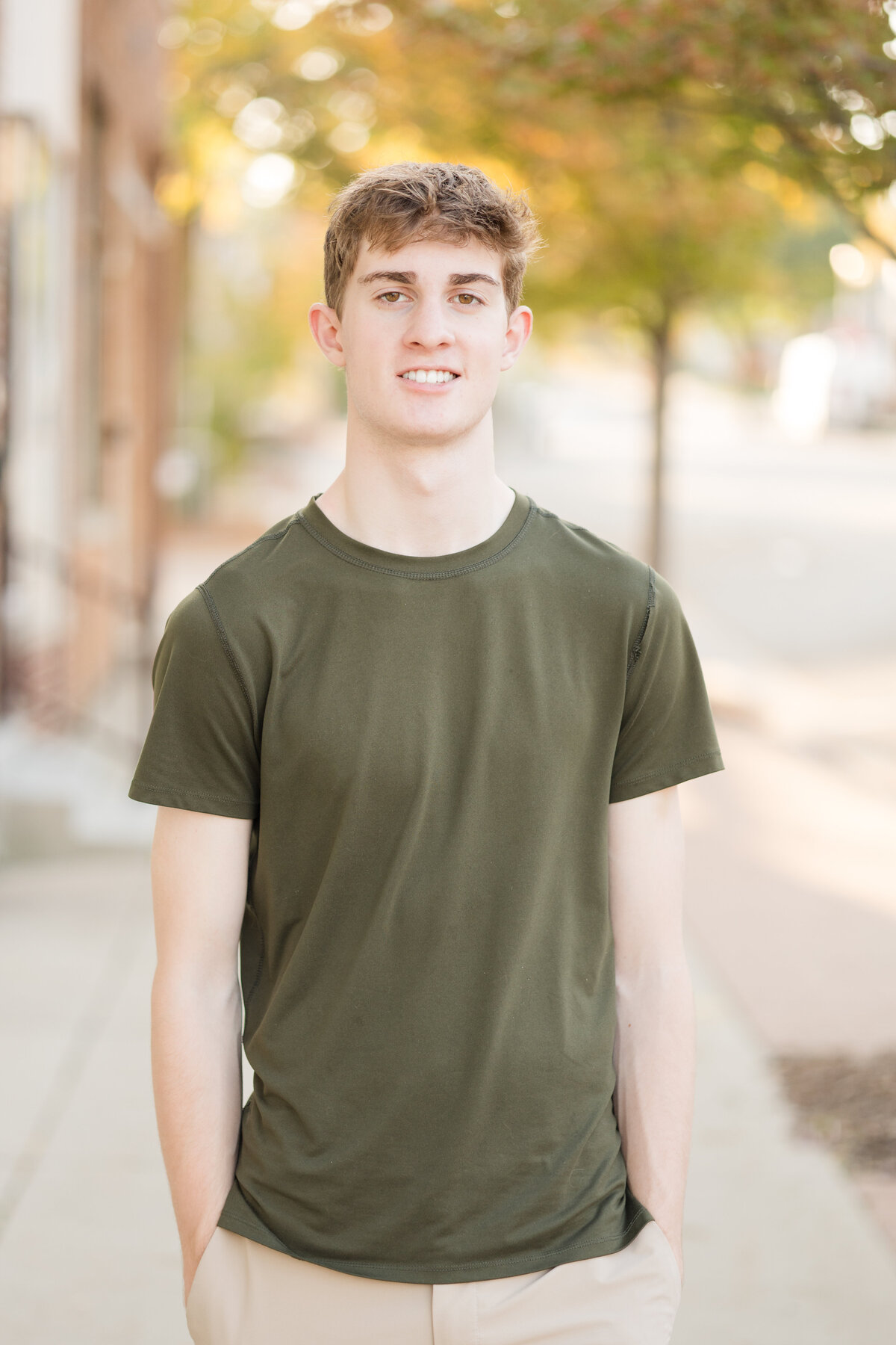 Senior guy standing on the sidewalk smiling at the camera
