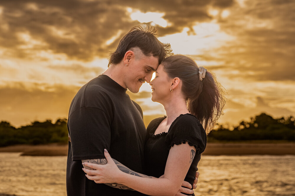 man and woman in black resting foreheads together and looking at each other with love at the beach at sunset - Townsville Engagement Photography by Jamie Simmons