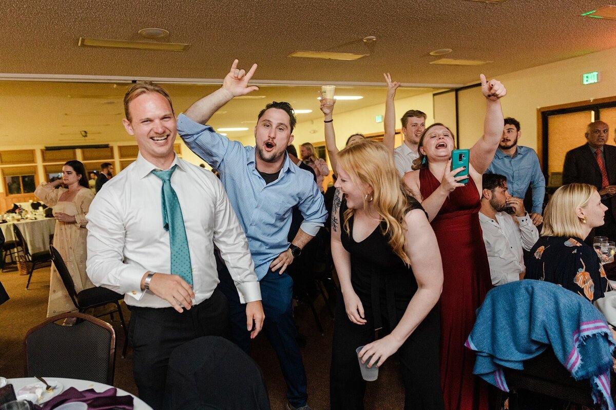 A group of wedding guests celebrating, dancing, and cheering during a wedding reception at the YMCA of the Rockies in Estes Park, Colorado.