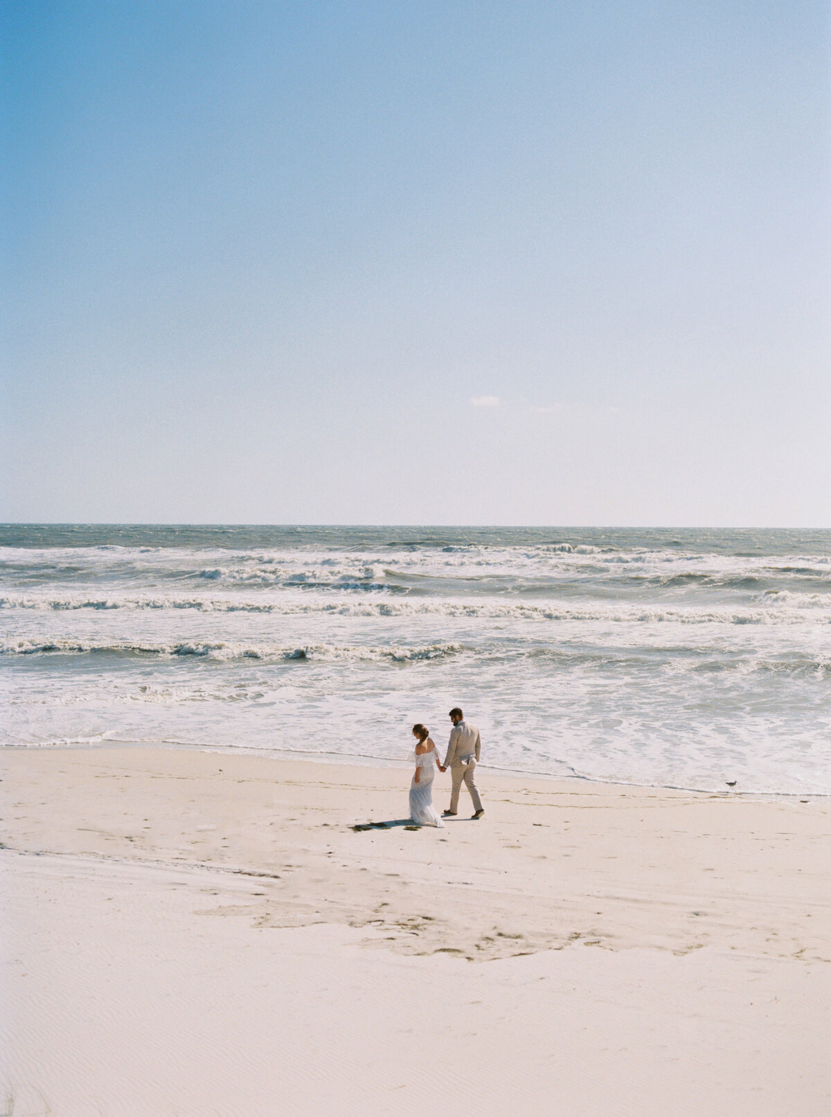 Bride and groom walk along a beach