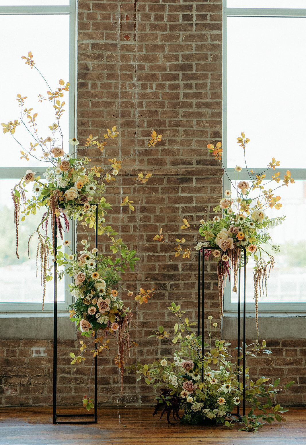 Orange and green flower arrangements in front of a brick wall at Entrepot Dominion.