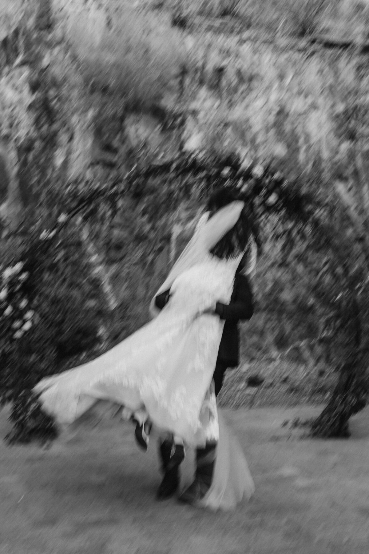 groom picked up bride in a celebratory twirl motion blur black and white film image