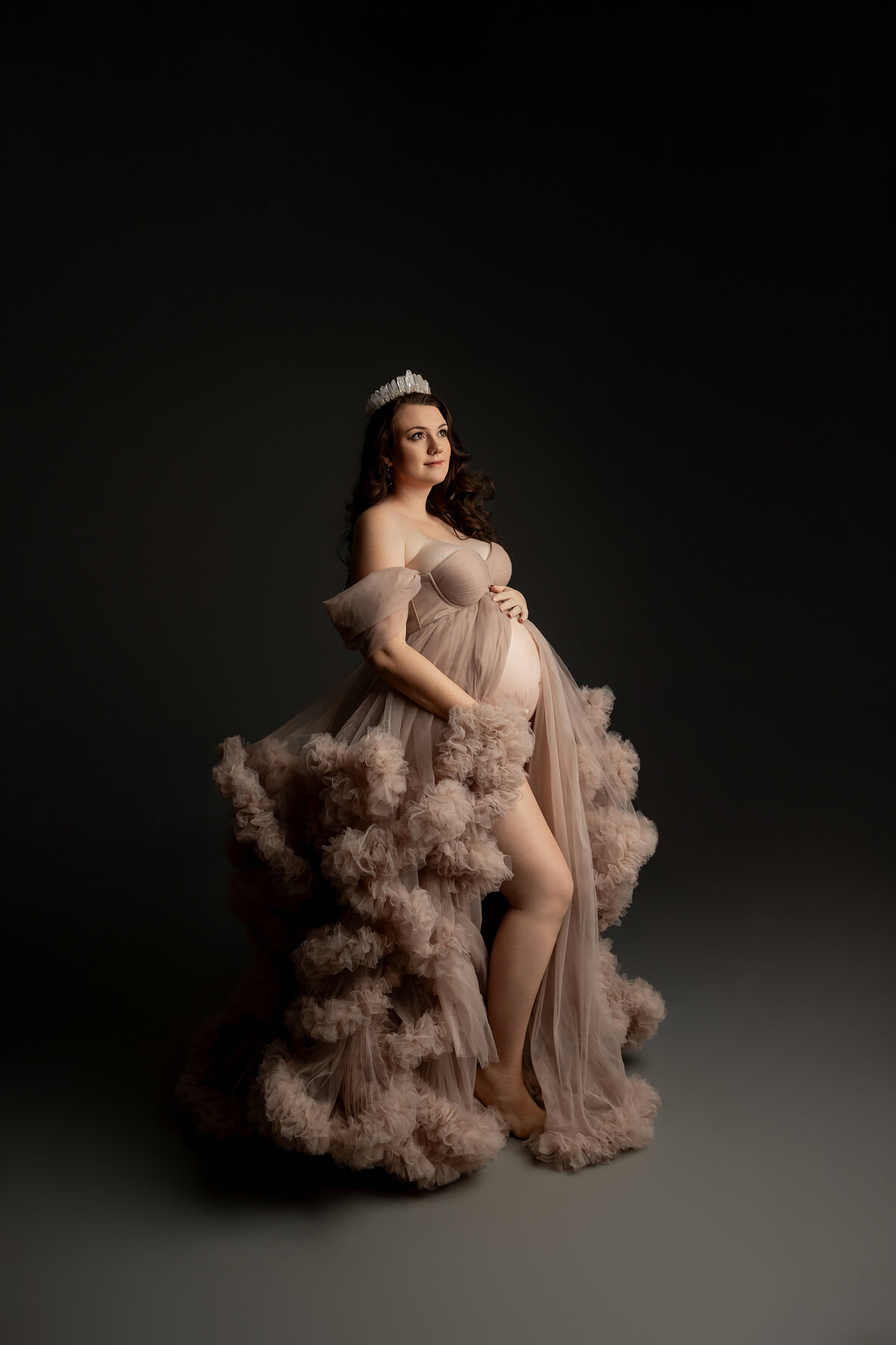 Wearing a soft beige dress and a delicate crown, the mother-to-be poses with grace, embodying elegance and anticipation for her growing family. Captured by Inland Empire maternity photographer Kaitlyn Dawn Photography.