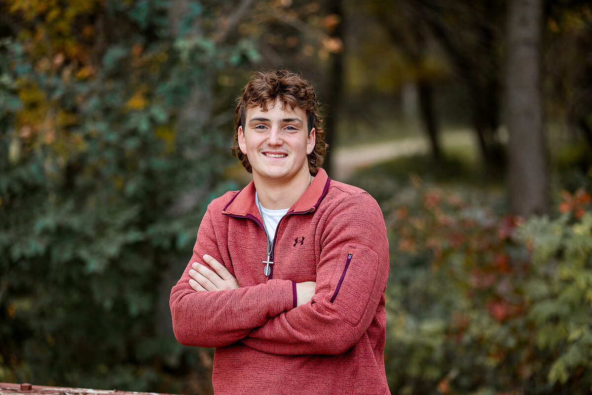 Wearing a maroon under armour sweatshirt, and senior guy poses for his pictures.