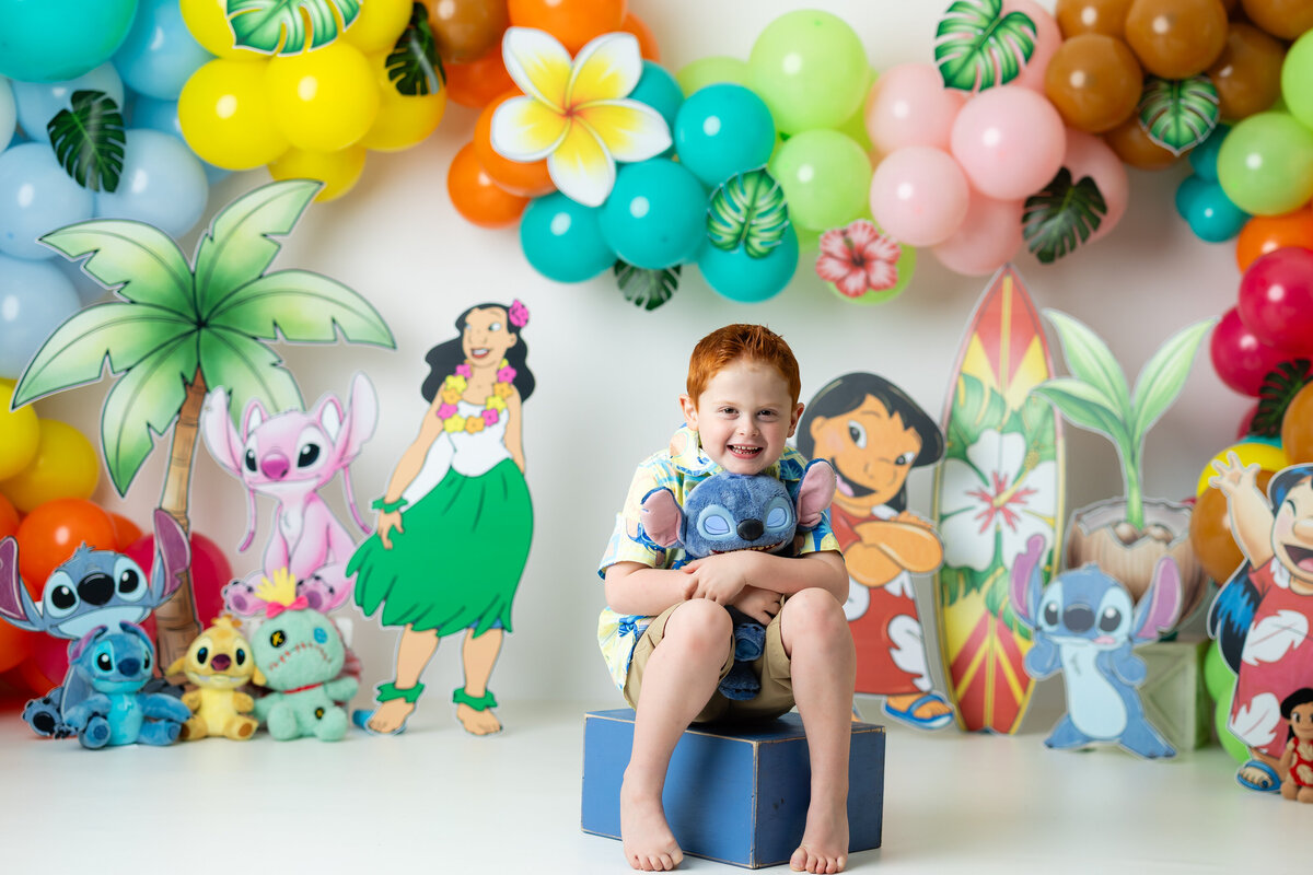 Boy having a tropical Lilo & Stitch-themed birthday session, featuring fun props and colorful decorations, captured by Victoria Lee Photography in Canton, GA.