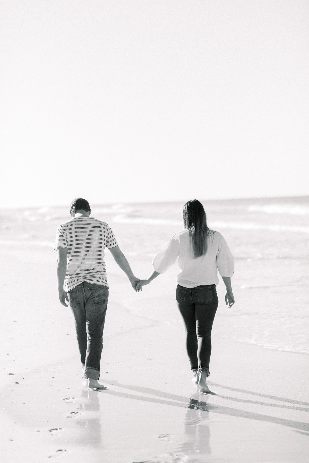 Couple holding hands on the beach captured by Staci Addison Photography