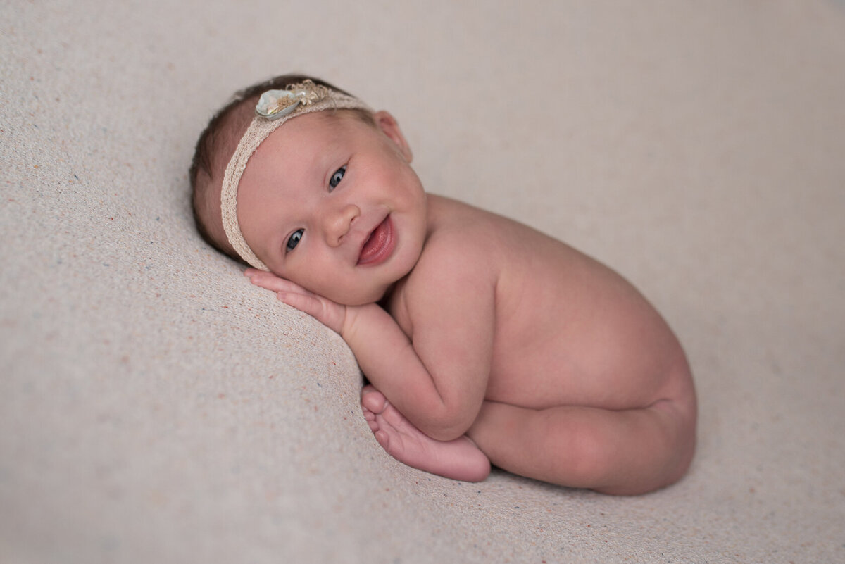 Smiling newborn chin on hands photography by Laura King