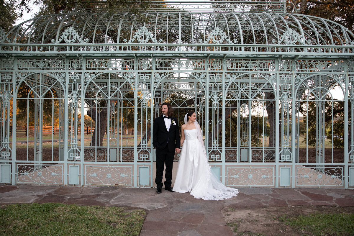 A bride and groom standing in front of an ornate gazebo, captured beautifully by an Austin wedding photographer.