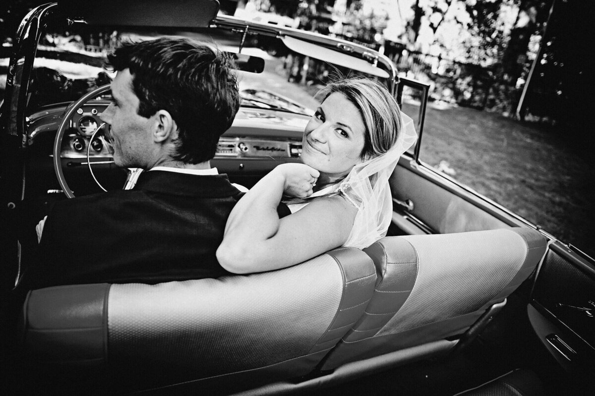 Bride and groom in vintage mustang bride looking camera over shoulder