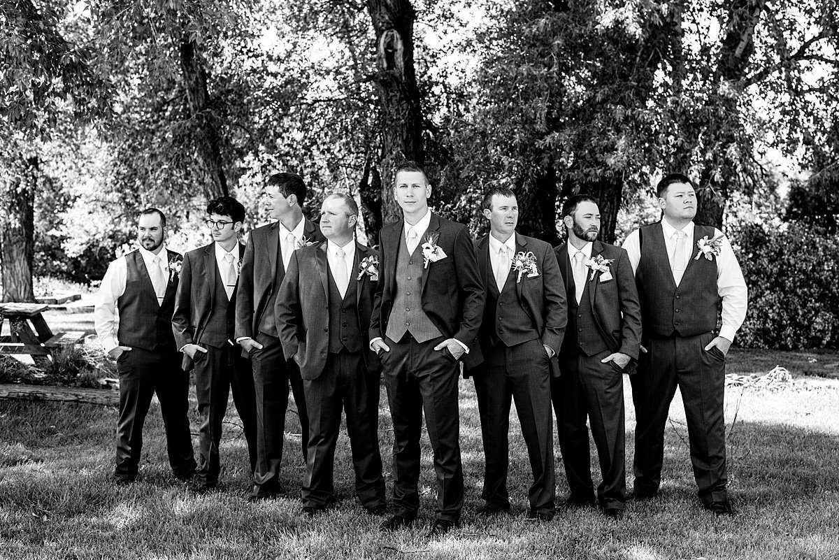 Black and white dramatic photo of groom standing with his groomsmen
