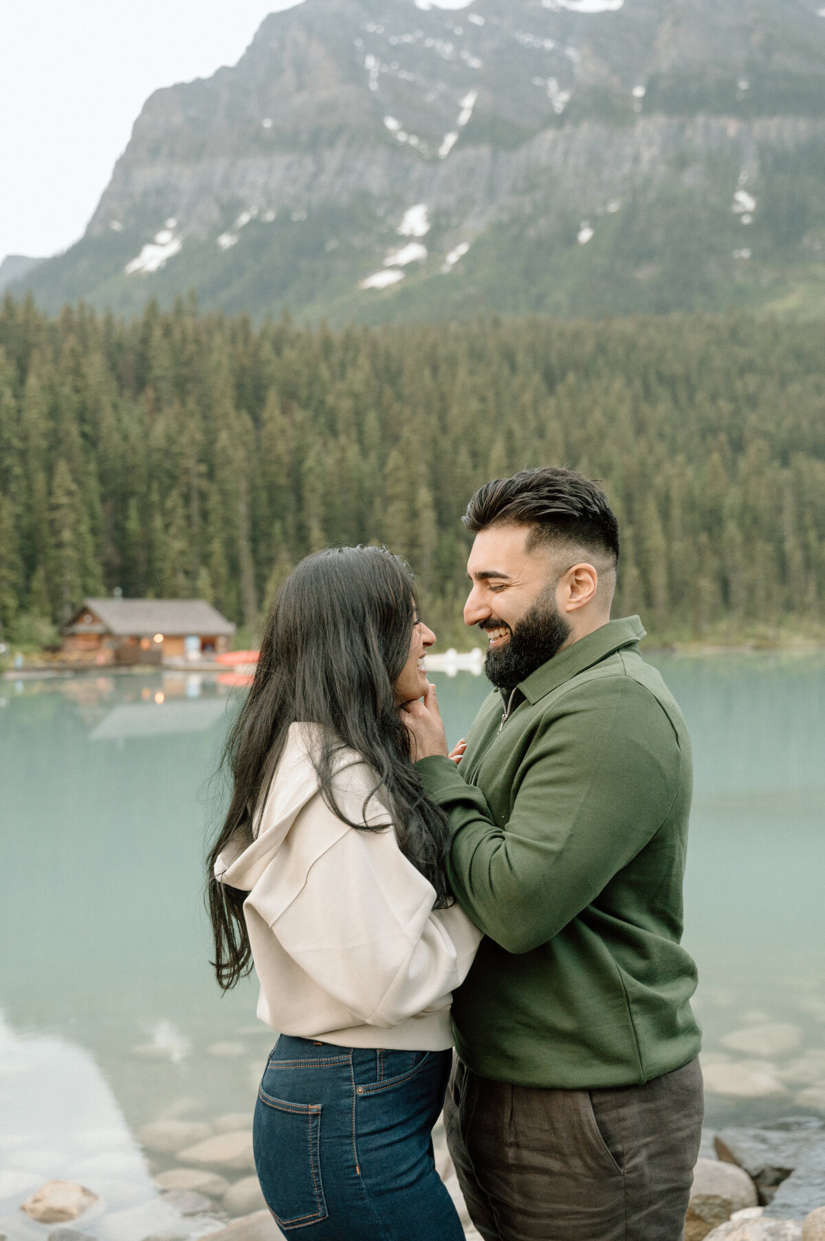 man holding woman's face before he kisses her during an engagement session in lake louise.