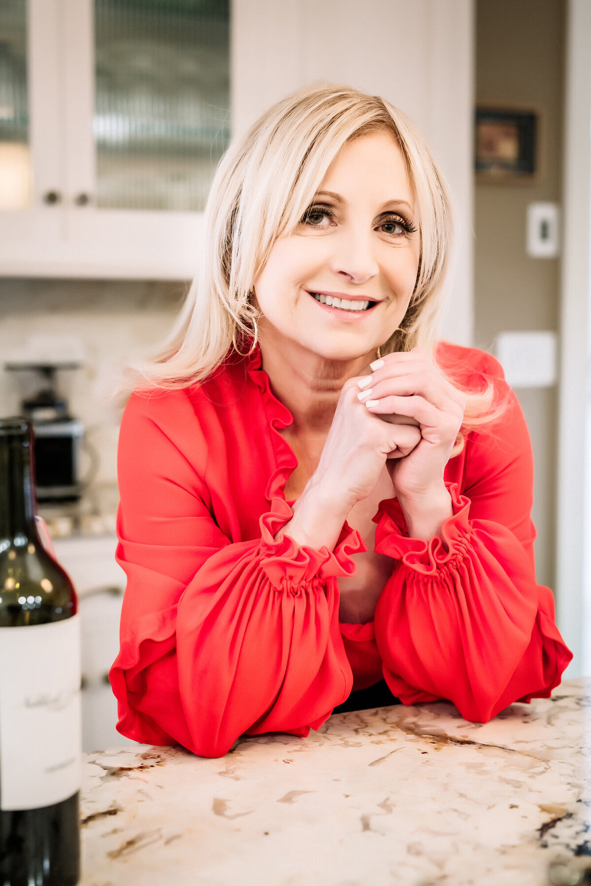A female dating portrait client. client leaning on her counter with her elbows, wearing a red blouse