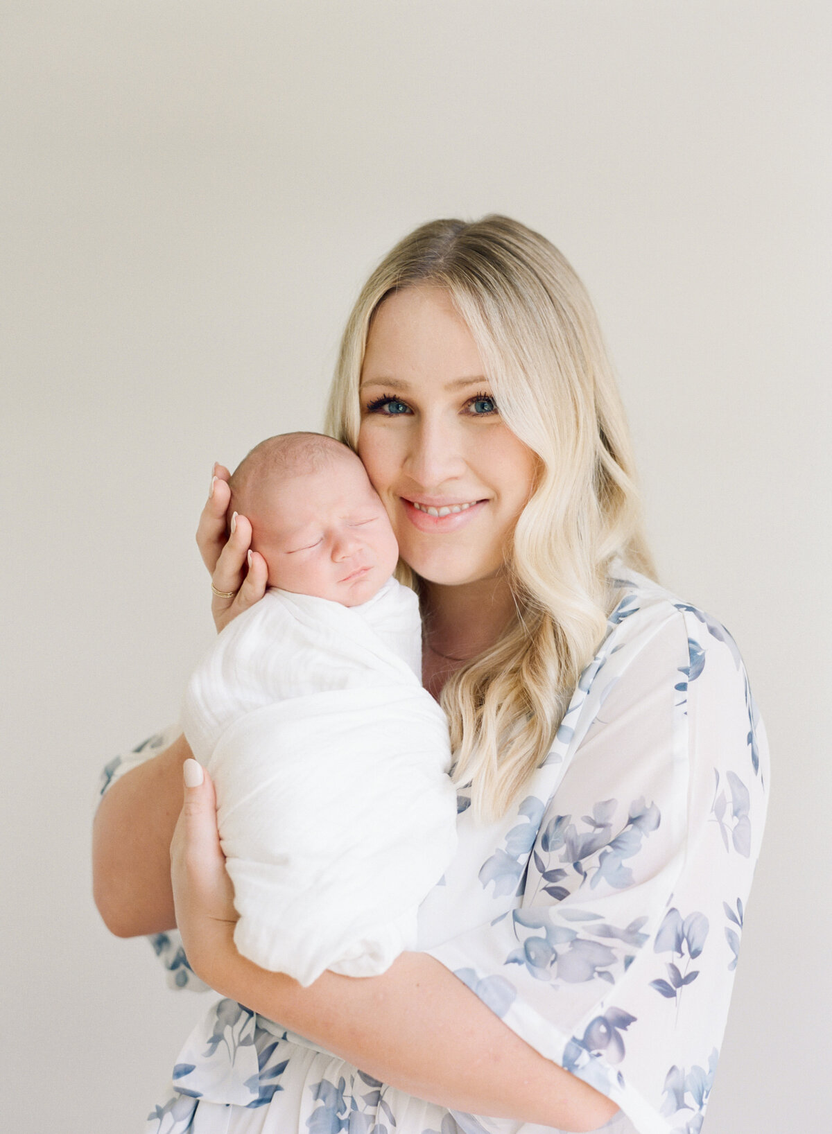 Mom holds her newborn close to her and snuggles him during a newborn session in Wake Forest NC. Image by Raleigh newborn photographer A.J. Dunlap Photography.