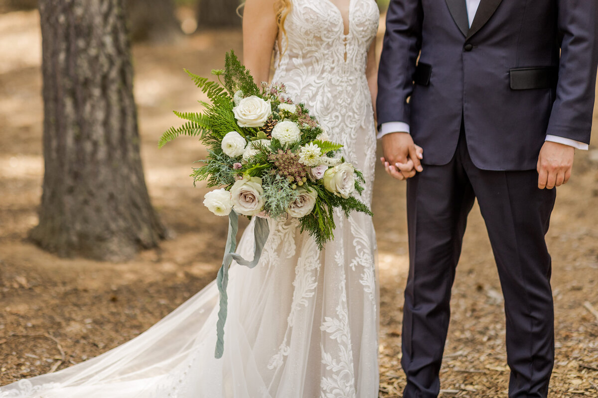 Bride and groom holding woodland wedding bouquet with ferns and roses