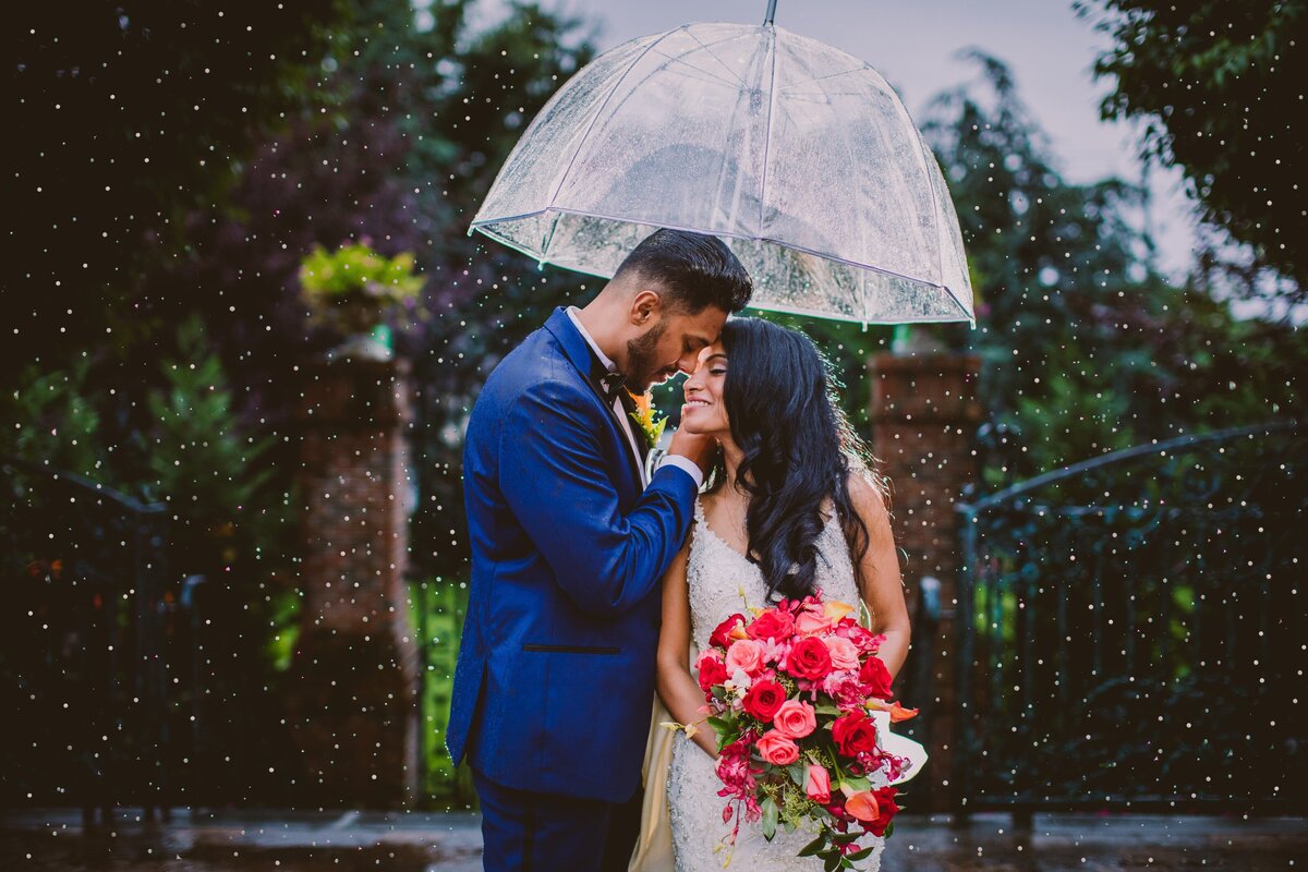 Indian christian bride and groom share a moment under the umbrella in the rain at the new hyde park inn in long island