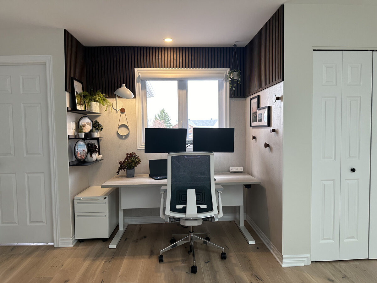 Modern home office with sit stand desk, dual monitors on articulating arms and ergonomic office chair, designed and installed by Urbanomic Interiors in Barrhaven (Ottawa).