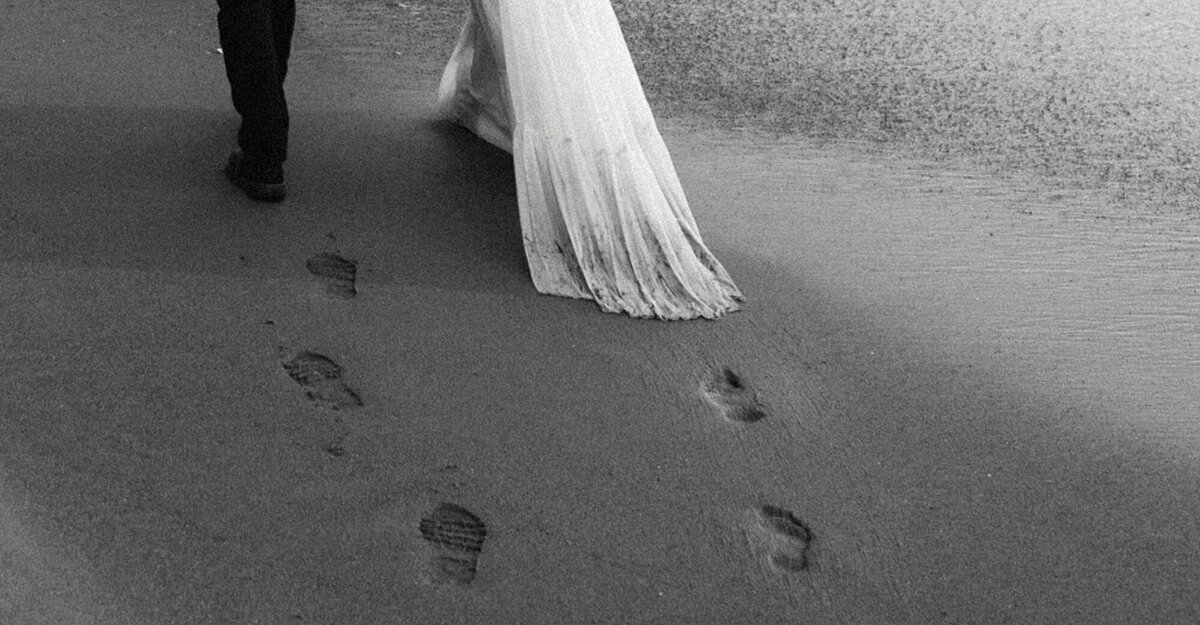 couple walking on beach and leaving footsteps