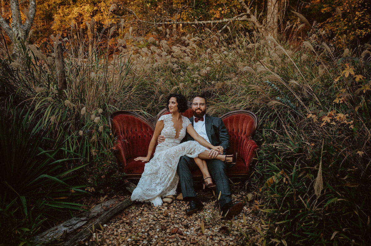 wedding couple sitting on vintage red couch  at neverland farms georgia 