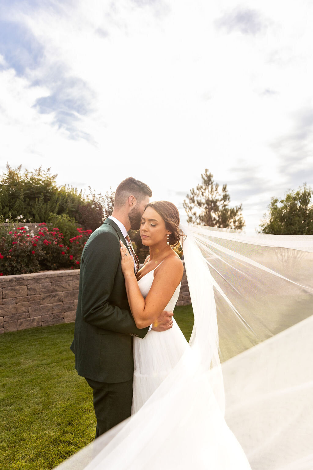 Bride and groom post for photos after their wedding ceremony with her veil blowing in the wind.