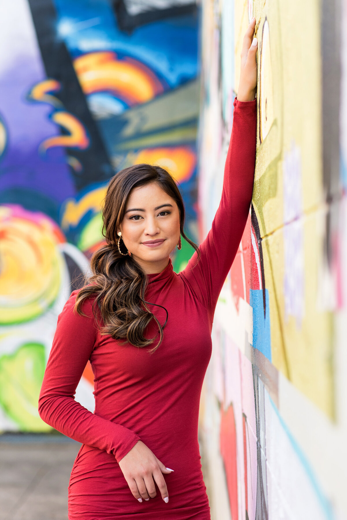 Richmond high school senior girl stands with one hand on wall and one hand on hip in front of murals at Canal Walk.