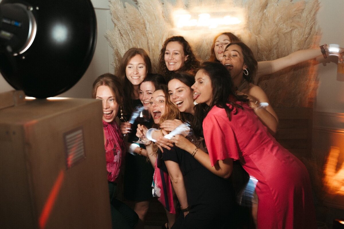 Un groupe d'amies pose devant un photobooth, rires et folie au rendez-vous. Mariage au domaine des Longrais en Bretagne immortalisé par Kamescop, vidéaste et photographe.