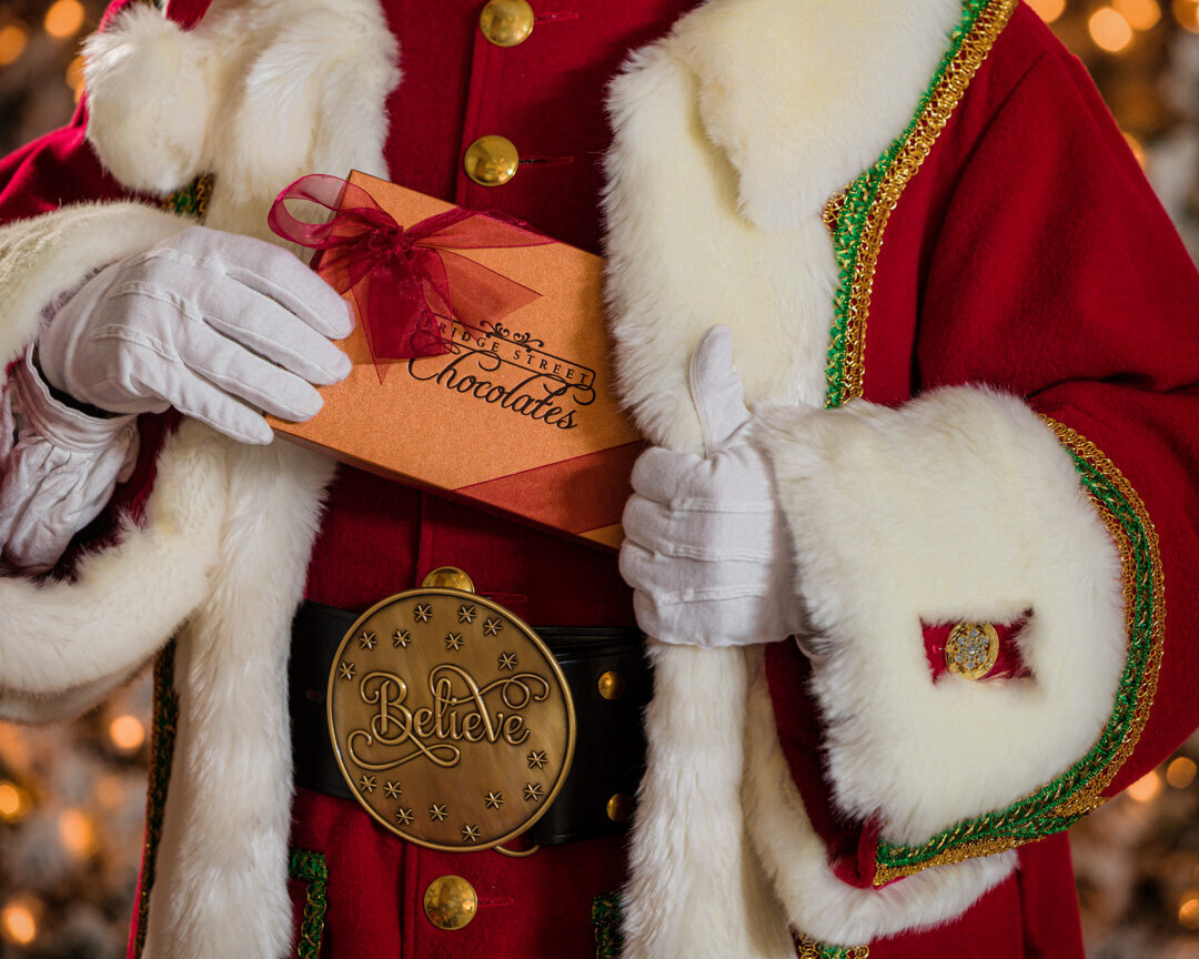 Commercial advertising photo of Santa Claus putting a box of cholocaltes in his coat