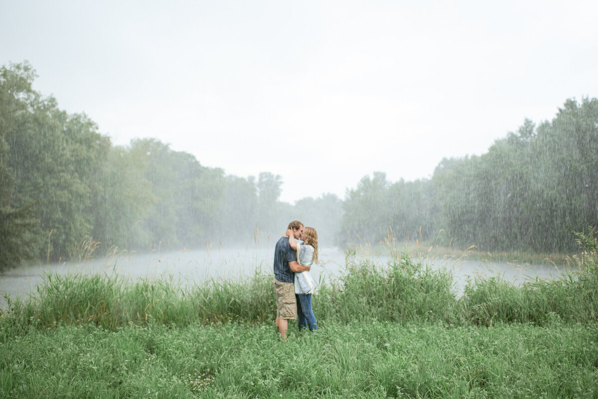 man and woman kiss while rain pours down around them
