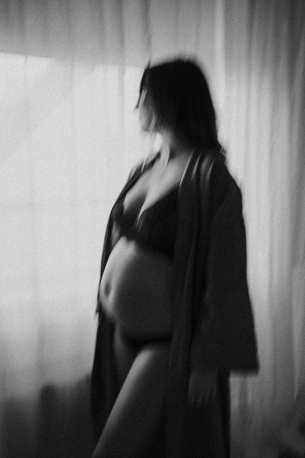 zwangere vrouw staat in lingerie voor het raam, bewegend beeld