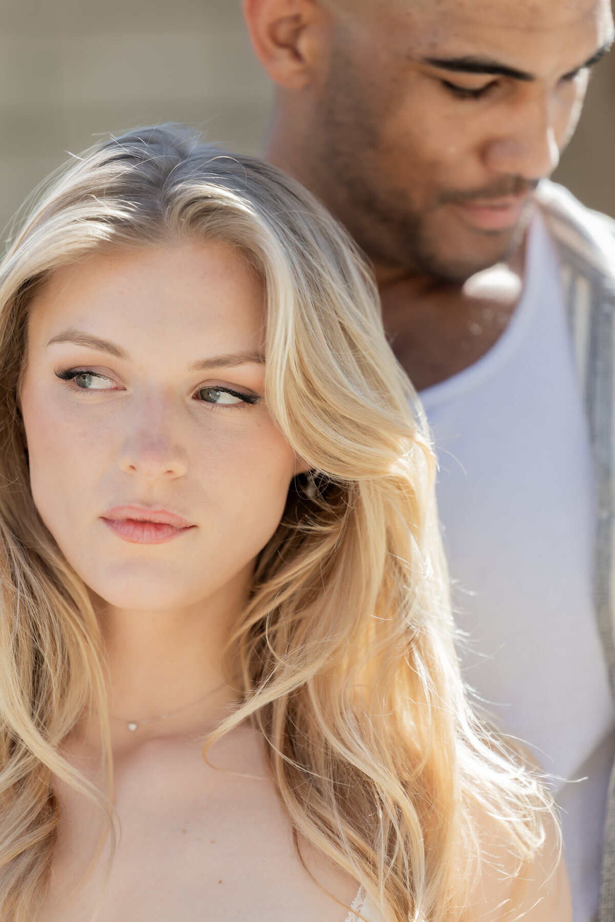 Close-up of couple forehead to forehead, embracing tenderly in soft desert sunlight.