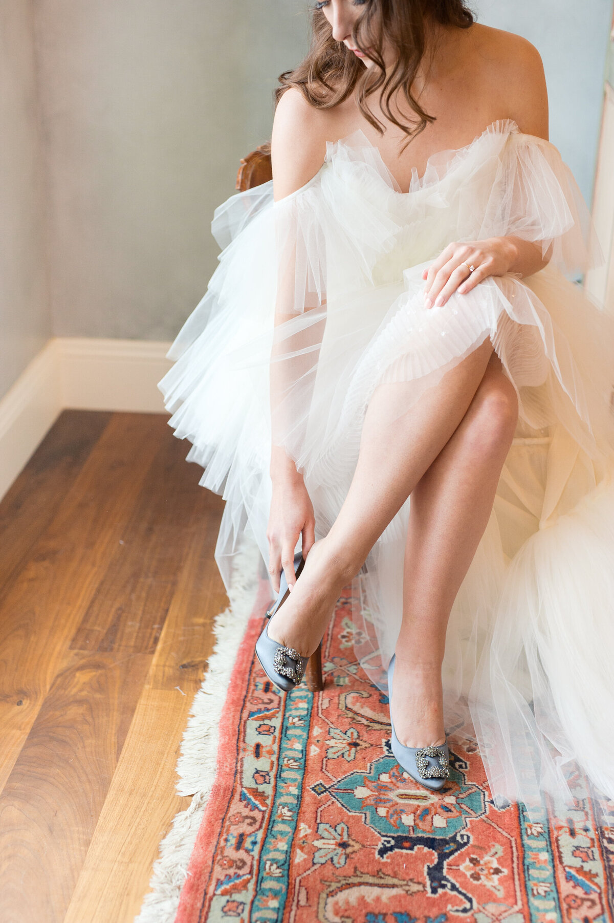 luxury bride putting on blue manolo blahnik shoes at chateau de lis in oregon