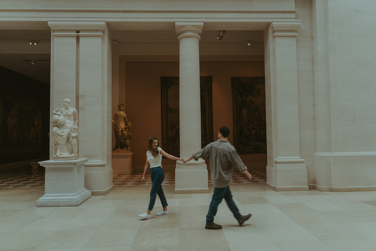 couple walking in the Met during NYC engagement photoshoot, captured by Elsie Goodman, an NYC engagement and couples photographer