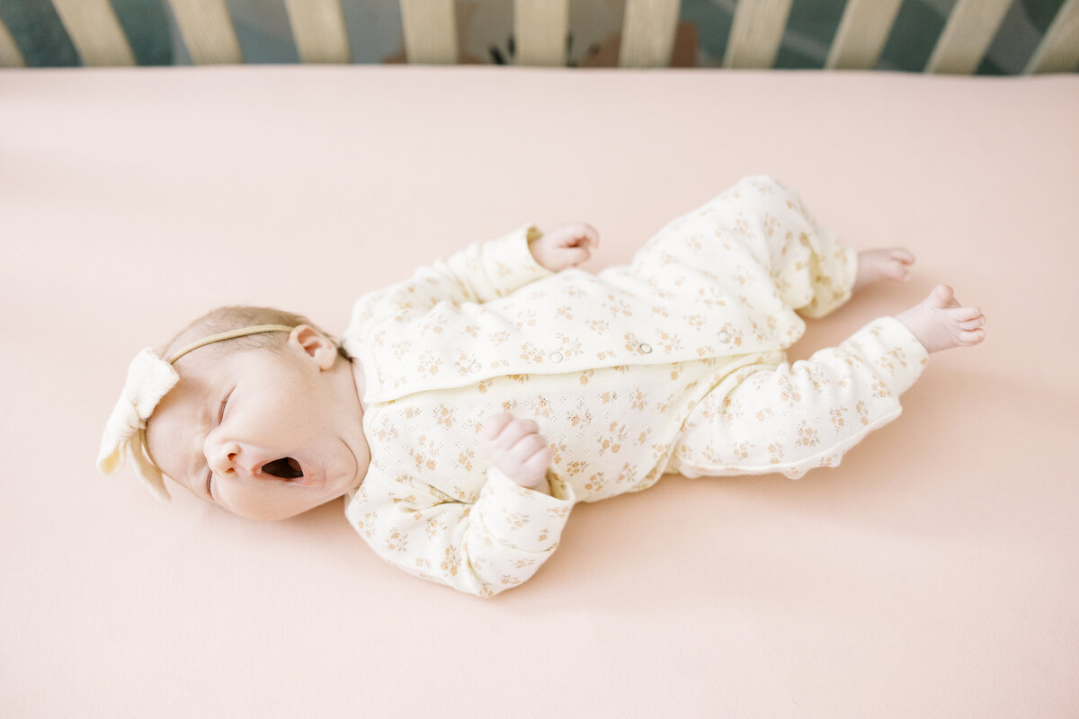 newborn baby girl yawning in her crib