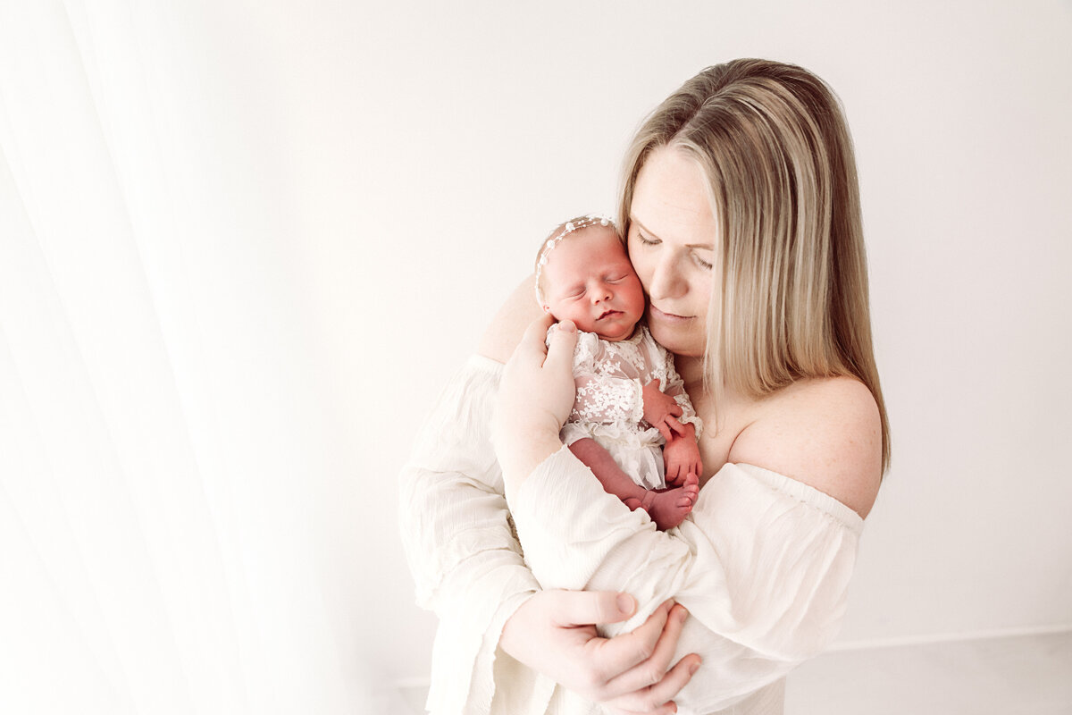 A tender moment between a mother and her newborn, wrapped in a loving embrace. Taken by Twin Cities Newborn Photographer, Fig and Olive Photography.