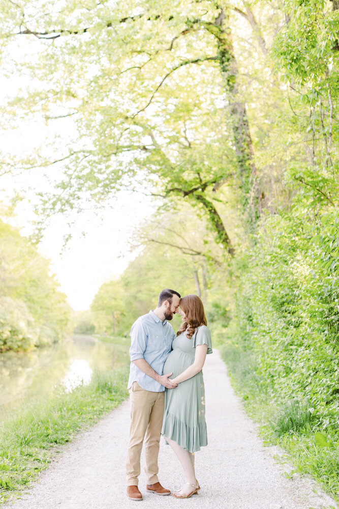 a man and pregnant woman embracing on a nature trail