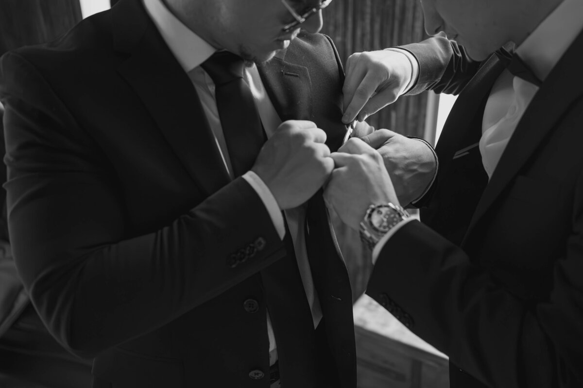 Groomsmen helping each other get ready for the wedding day.