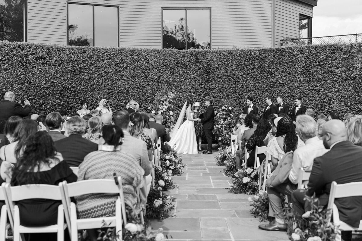 Black and white outdoor photo of a summer wedding ceremony at The Roundhouse