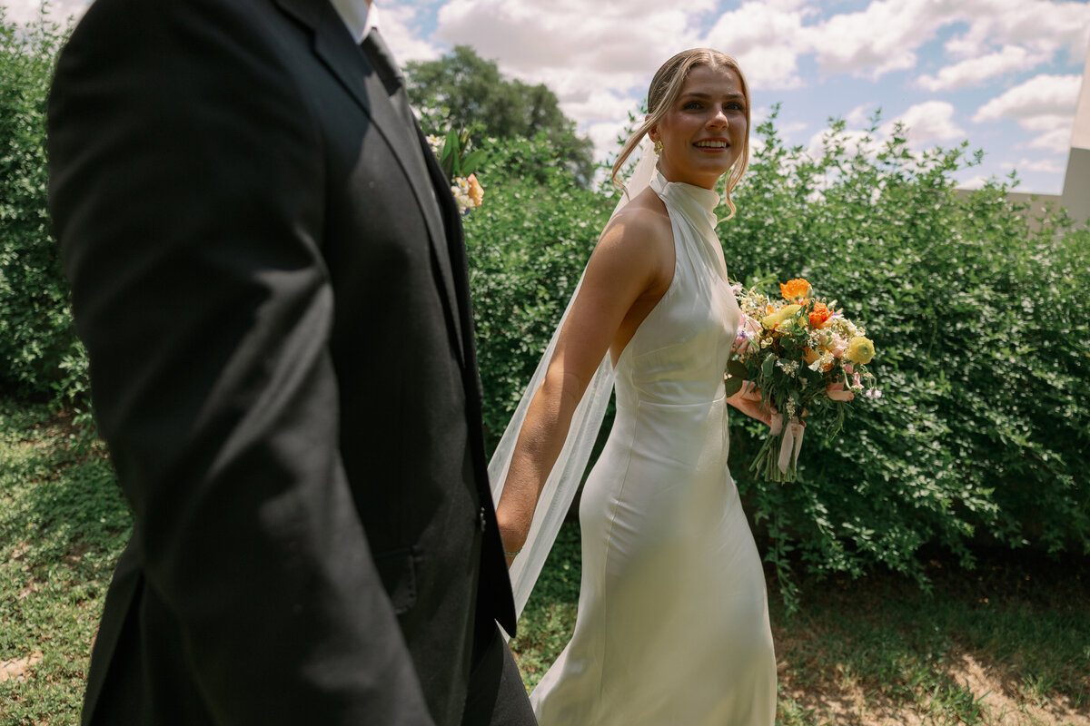 Eloping couple hand in hand in a field in Maine