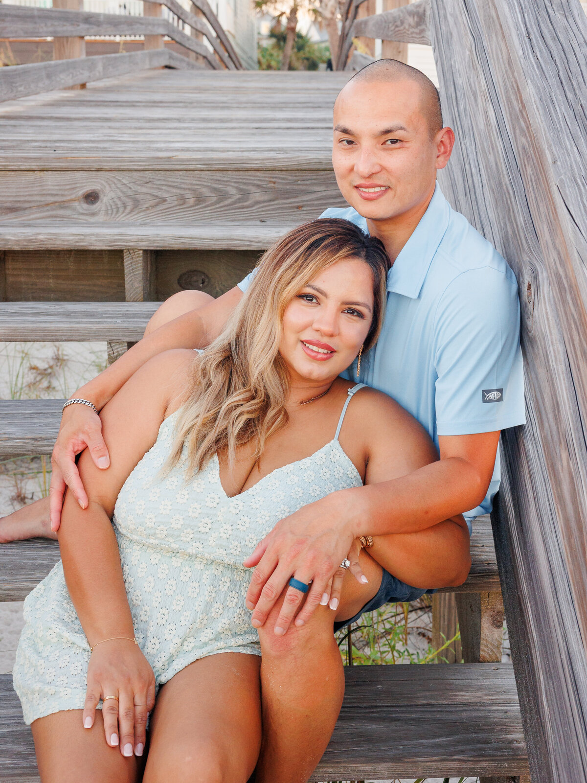 husband and wife in sitting pose on boardwalk steps at beach during summer
