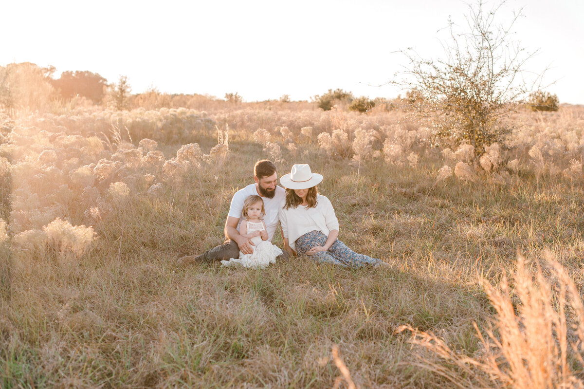 Orlando Maternity Photographer captures a stunning image of the golden hour glow, while the family all look in admiration at the moms belly.