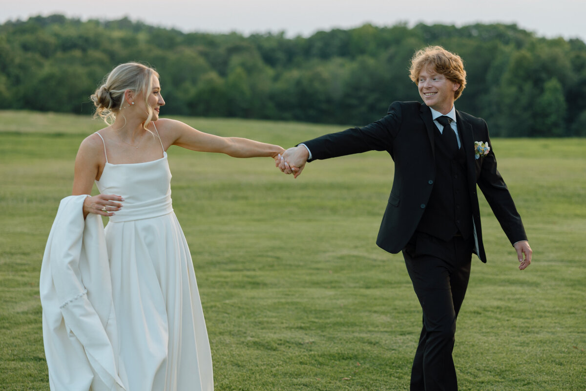 Bride and groom walk hand in hand at sunset