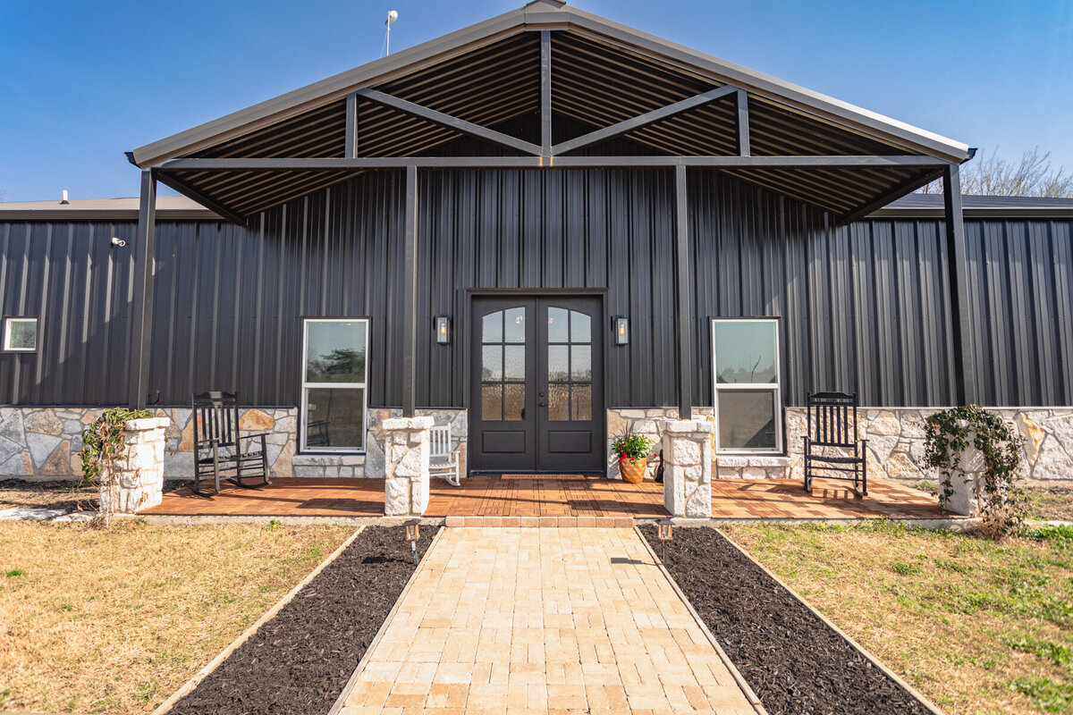Front porch and main entry at this five-bedroom, 3-bathroom vacation rental house for up to 10 guests with free wifi, private parking, outdoor games and seating, and bbq grill on 2 acres of land near Waco, TX.