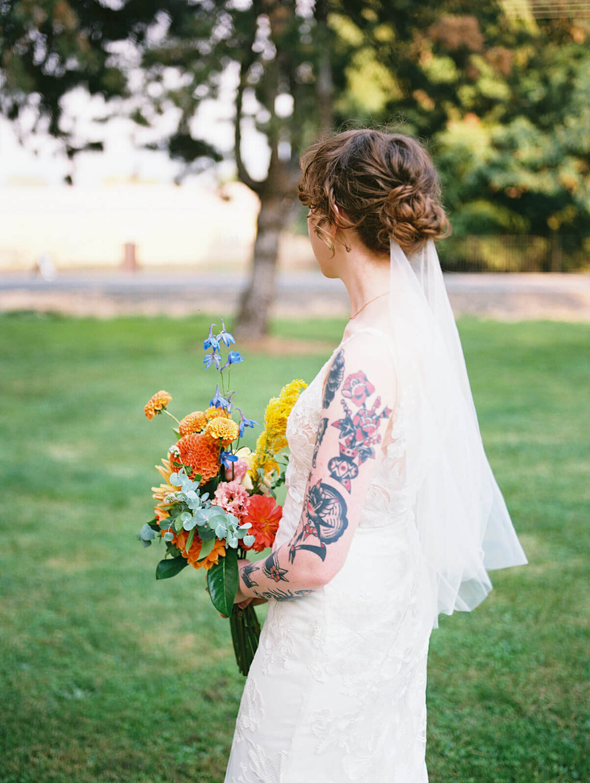 A bride captured from the side to show off her tattoos and vail. 