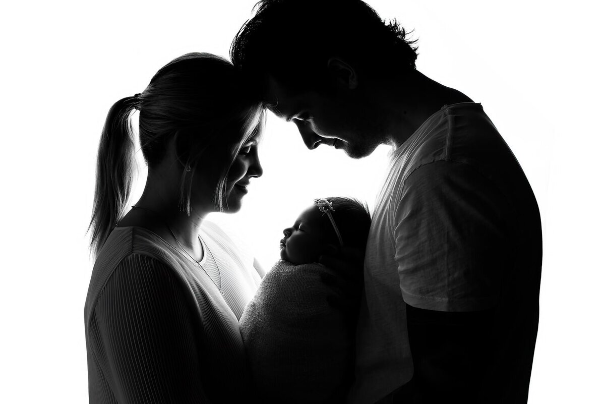 Black lighting parent and newborn baby black and white portrait